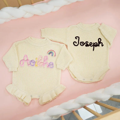 Two baby rompers with embroidered names on a pink surface