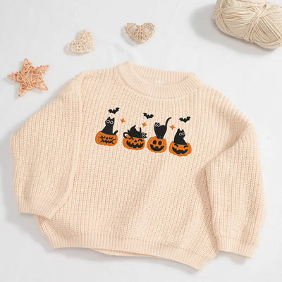 Beige sweater with Halloween design featuring cats and pumpkins on a light gray background.