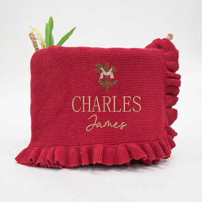 Red knitted blanket with embroidered name and logo on a white background