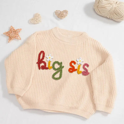 Beige sweater with 'big sis' text on a light background
