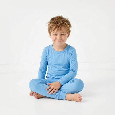 Child wearing a blue outfit sitting on a white background
