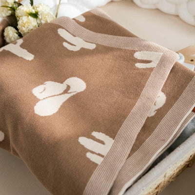 Brown blanket with white floral pattern on a wooden surface