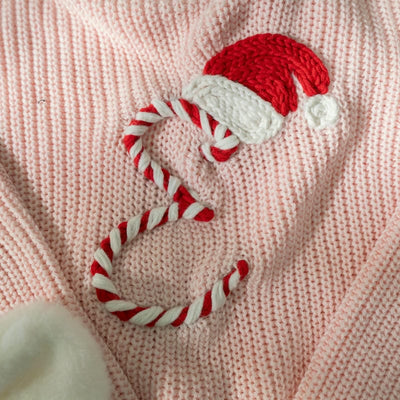 Crocheted Santa hat and candy cane on a pink knitted fabric background
