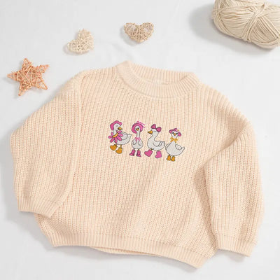 Beige sweater with embroidered ducks on a light gray background