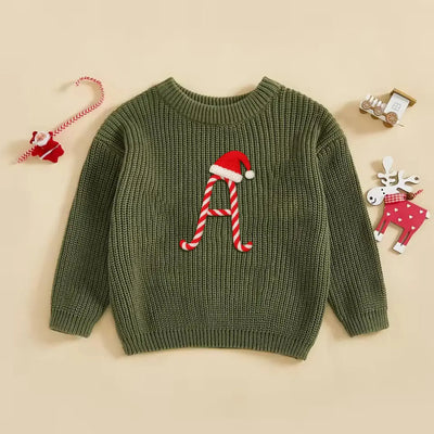 Green sweater with a letter 'A' design featuring a candy cane and Santa hat on a beige background.
