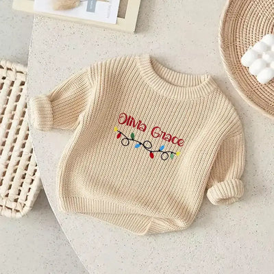 Beige baby sweater with 'Olivia Grace' embroidered on a light surface