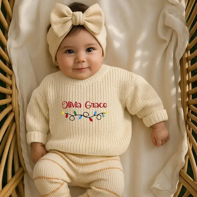 Baby wearing a cream sweater with 'Olivia Grace' printed on it, sitting in a wicker basket.