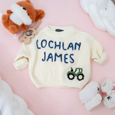 Children's sweater with 'LOCHLAN JAMES' text and tractor design on a pink background