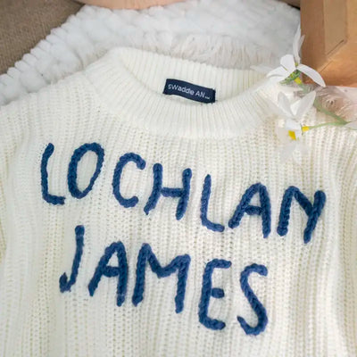 White sweater with 'LOCHLAN JAMES' text and a visible brand tag.