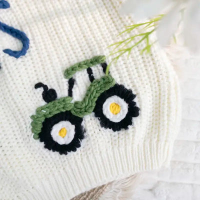Embroidered green tractor design on a white fabric background