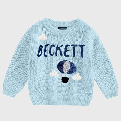 Light blue sweater with hot air balloon design and 'Beckett' text on a light gray background