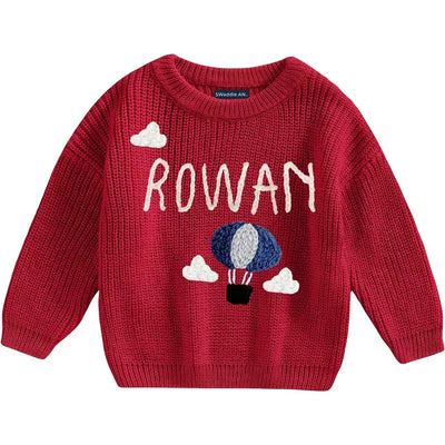 Red sweater with 'ROWAN' and hot air balloon design on a white background