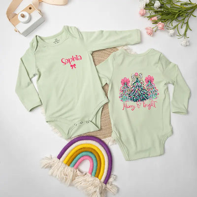Two green baby onesies with text and graphics on a light gray background with decorative items.