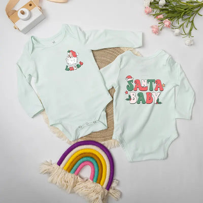 Two light green baby onesies with Christmas-themed designs on a neutral background.