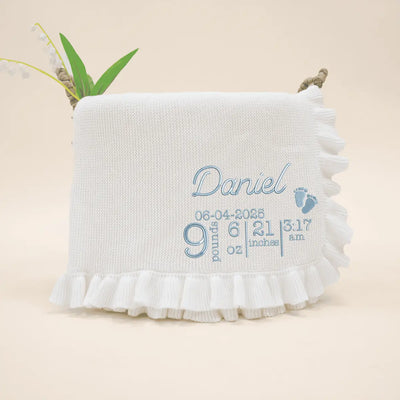 White baby blanket with embroidered text on a beige background