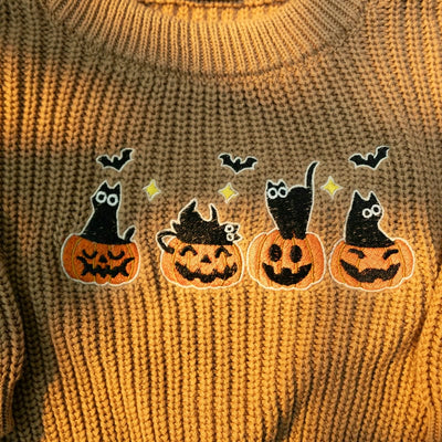 Knitted sweater with Halloween-themed patches of pumpkins, cats, and bats.