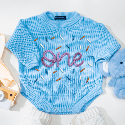Blue baby sweater with 'one' design on a white background