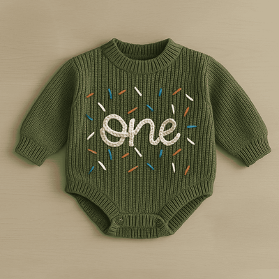 Green baby onesie with 'one' embroidered on a beige background