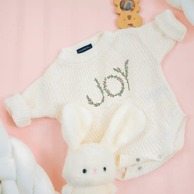 White knitted sweater with floral design on a pink background