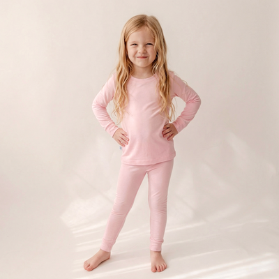 Young girl wearing pink pajamas on a plain background