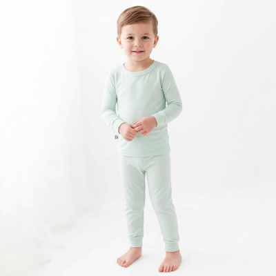Child wearing a light green pajama set on a white background