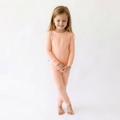 Young girl wearing peach pajamas on a white background