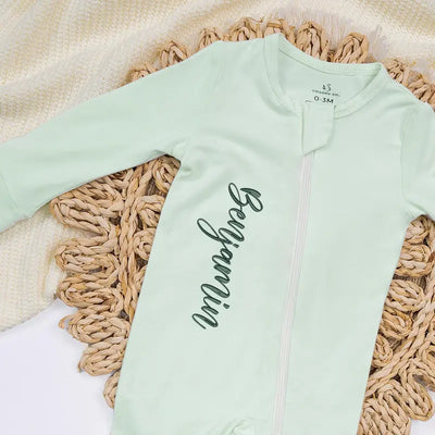 Light green baby onesie with text on a woven mat