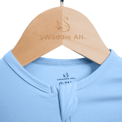 Blue baby outfit on a wooden hanger with 'Swaddle AN' branding.