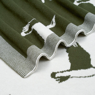 Knitted blanket with animal patterns in green and white on a white background