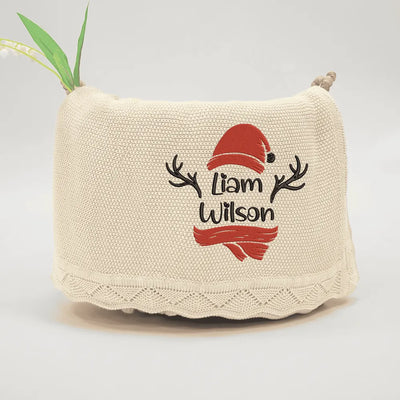 Beige personalized baby blanket with embroidered christmas design and text on a light gray background