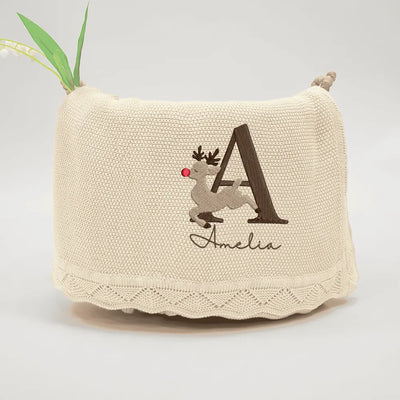 Beige personalized baby blanket with embroidered letter 'A' and name 'Amelia' on a light gray background