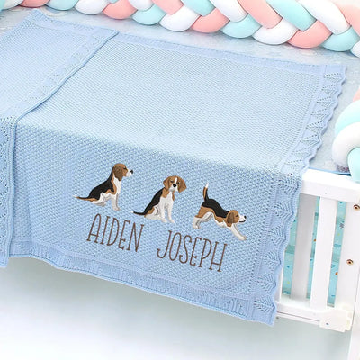 Blue baby blanket with embroidered beagle puppies and names on a crib