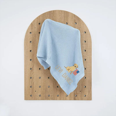 Light blue personalized baby blanket with embroidered patriotic golden retriever design on a wooden board