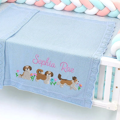 Blue personalized baby blanket with embroidered shih tzus and name 'Sophia Rae' on a crib.