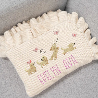 Cream personalized baby girl blanket with embroidered dachshunds and 'Evelyn Ava' on a gray surface