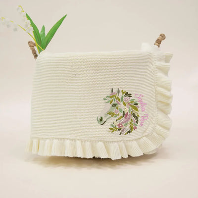 Cream personalized baby blanket with floral horse design on a light background