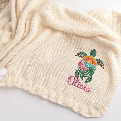 Cream personalized baby blanket with a sea turtle design and 'Olivia' text on a white background