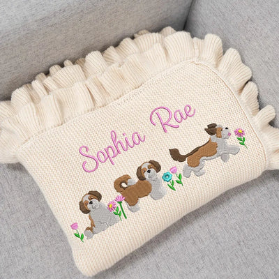 Personalized baby blanket with embroidered shih tzu dogs and 'Sophia Rae' text on a gray surface