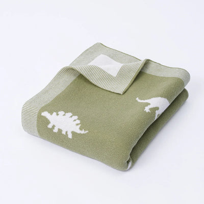 Folded green blanket with white dinosaur patterns on a white background