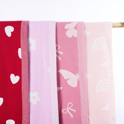 Four pink scarves with different patterns on a wooden rod.