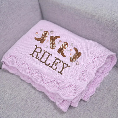 Lilac personalized baby blanket with embroidered name and cowgirl boots designs on a gray surface