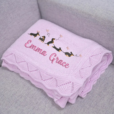 Lilac personalized baby blanket with embroidered name and dachshunds on a gray surface