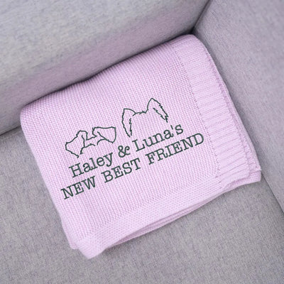 Lilac personalized baby blanket with embroidered text and dog ears on a gray surface