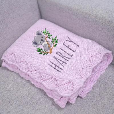 Lilac personalized baby blanket with a koala design and embroidered name 'Harley' on a gray surface.