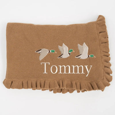 Mocha knitted baby blanket with embroidered mallard ducks and 'Tommy' text on a white background