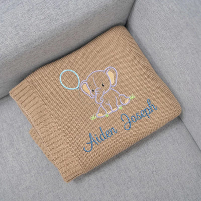 Personalized baby blanket with embroidered elephant design and name on a gray surface