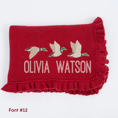 Red personalized blanket with embroidered mallard ducks and text 'OLIVIA WATSON' on a white background