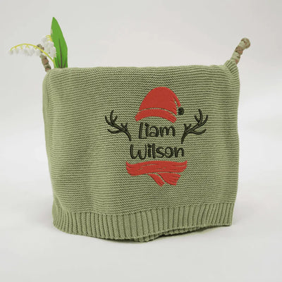 Sage green personalized baby blanket with embroidered text and red accents on a white background