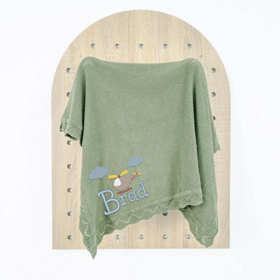Sage green personalized baby blanket with 'Brad' embroidery on a wooden board