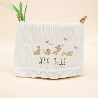 White personalized baby blanket with embroidered dachunds and 'Aria Belle' text on a beige background